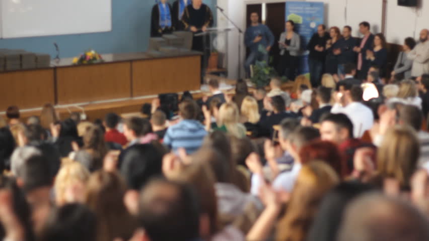 Students clap hands ,unrecognizable students and dean in the amphitheater