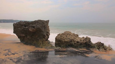Sea waves crashing rocks. Ocean beach coast landscape in the evening after sunset. Beautiful nature at twilight, dusk, dawn. Water rolling, splashing, spraying, foaming, crushing shore, stone, sand. 
