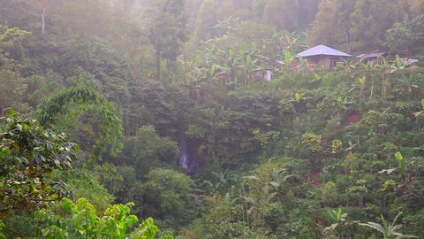 Village in tropical jungle forest, mountain nature landscape. Ethnic travel to Asia, rural houses at green hills view. Beautiful asian tourism among trees, grass and river. Traditional huts, culture.