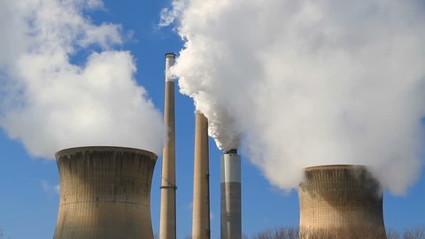 White smoke and steam billow from smokestacks and cooling towers against a vivid blue sky at an electricity generating power plant in West Virginia.