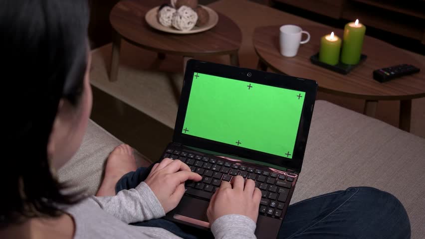 Young Japanese woman typing on keyboard, Asian girl using laptop pc with green screen, notebook computer monitor at home. Wireless technology for internet and wi-fi email, lifestyle, relaxation