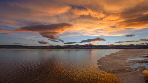 Sunset-To-Dusk at Spring Mountain Lake - Panoramic sunset-to-dusk time-lapse of colorful storm clouds rolling out rocky mountains front range and passing over an ice-melting spring lake.