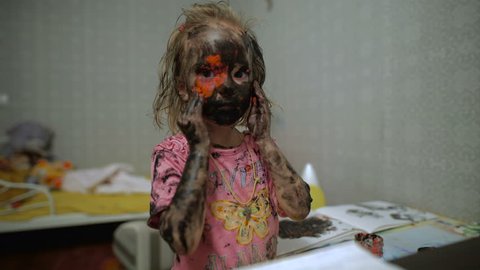 A small girl with paint all over her face.