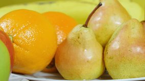 Arranged pears and orange in plate on the table,dolly shot,extreme close up,shallow depth of field,different kind of fruits in the blurred background,similar clip also in 24,25 and 30 fps,raw video.