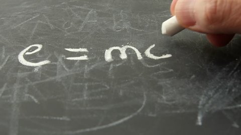 A man writes e equals mc squared on a chalkboard