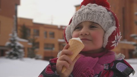 Little girl eating ice cream in winter