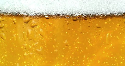 bubbles movement inside a glass of beer with drops and foam as background seamless loop