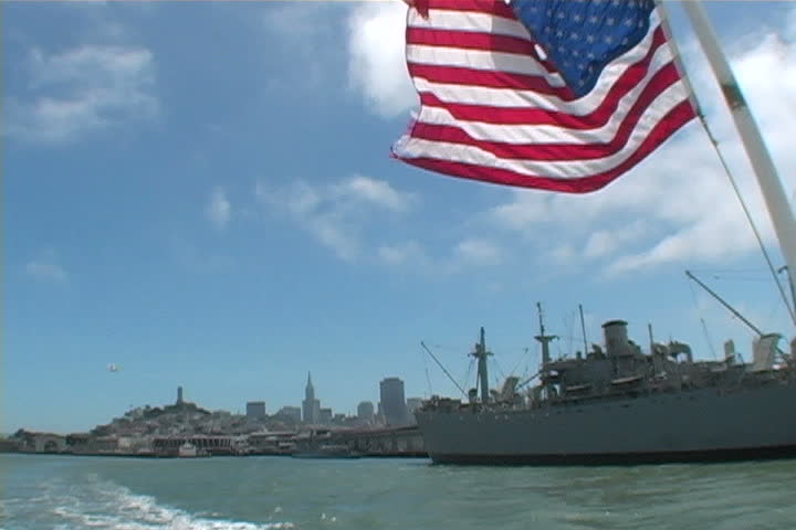The Flag flying high as it passes a WWII war ship in San Francisco.
