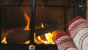 Fireplace and Woman feet against burning stove. Girl wearing socks in front of fireplace in living room. Female is warming her legs during winter. RED EPIC SLOW MOTION,