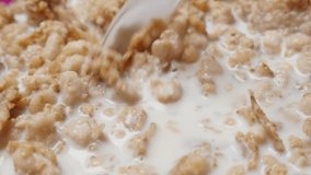 Close-up slow motion mixing crunch muesli breakfast with milk 1080p HD video - Cereal food meal mixed with milk plastic spoon closeup slow-mo 1920X1080 FullHD tilting footage