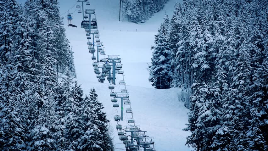 Chairlift Going Up Mountain Near Trees In The Snow