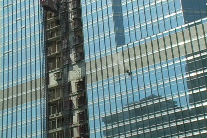 A man dangling from the side of building.
