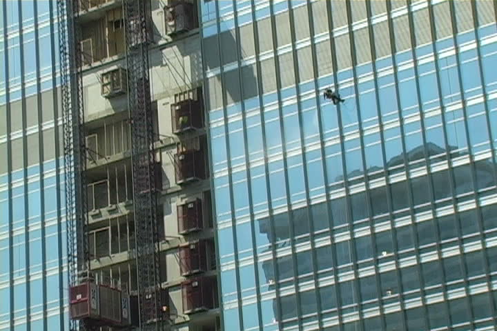 A man dangling from the side of building.