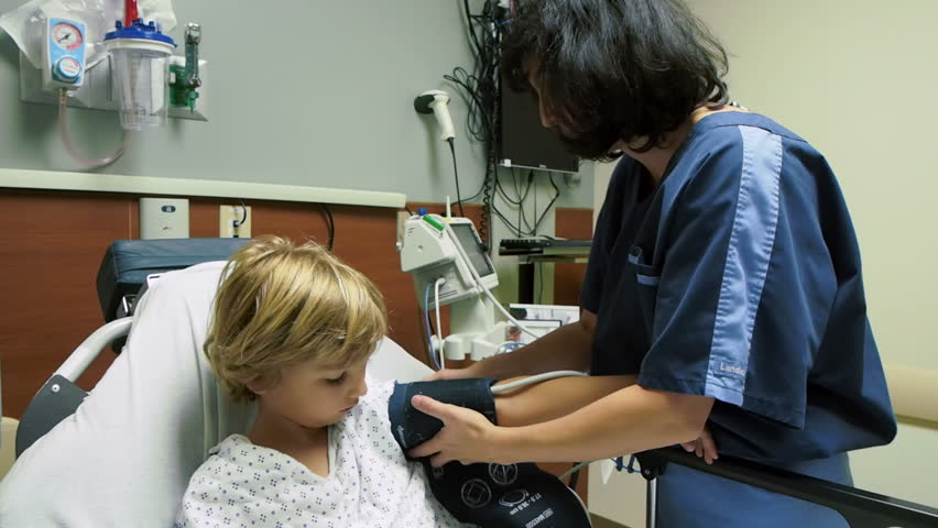 Nurse with little boy in hospital. Nurse giving loving care to young boy on stretcher in hospital. Child getting medical exam before surgery in medical center.