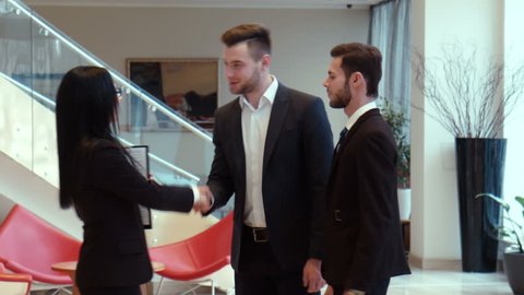 Meeting of three successful beautiful businessmen dressed in official suits, shaking hands 
