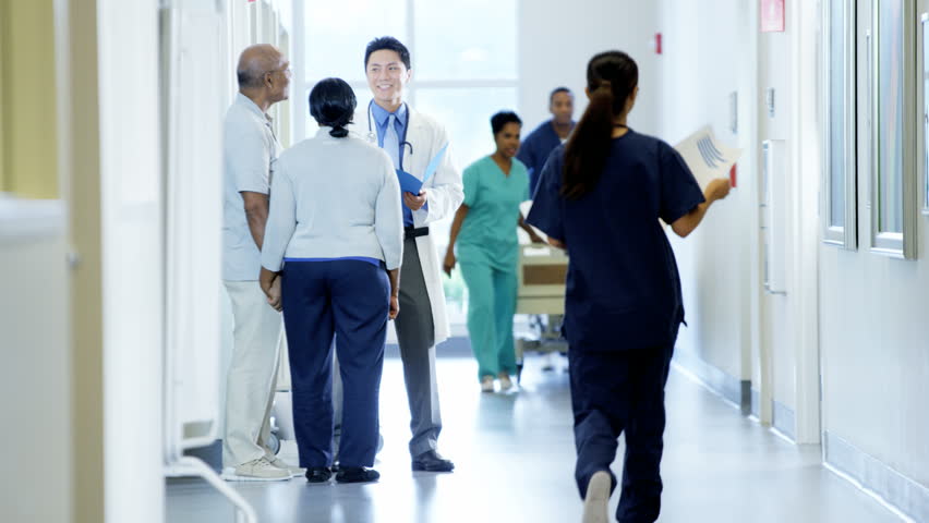 Staff of hospital work on corridor and male doctor consult with senior couple Royalty-Free Stock Footage #14611054