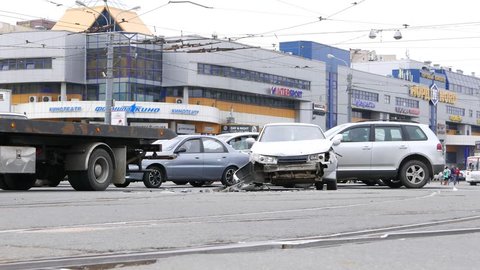 SAINT-PETERSBURG, RUSSIA - MAY 11, 2015: Car accident aftermath, broken front part of vehicle, stand in middle of road. Traffic around, urban street intersection. Other cars pass on background