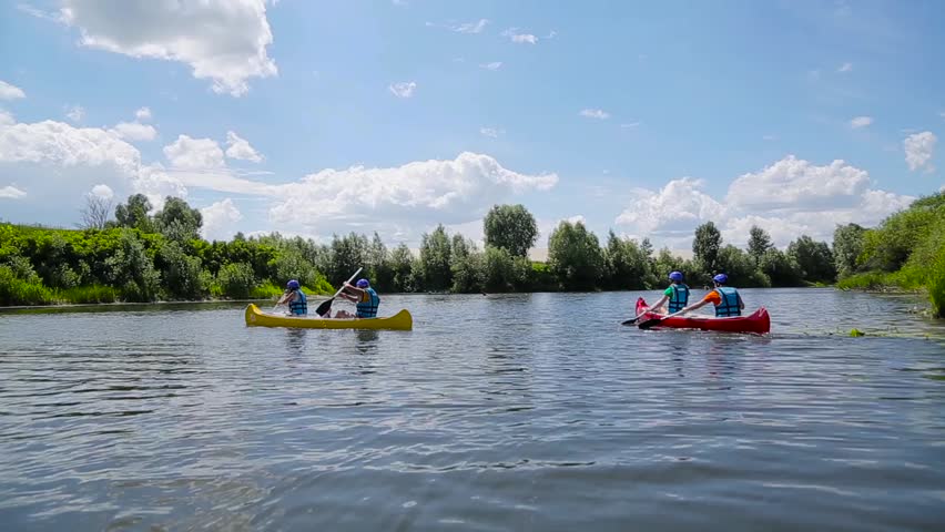 Two canoes with people floating on the river.