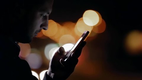 person works with the phone on the road at night