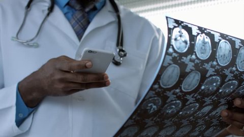 African american doctor viewing mri picture and using smart phone