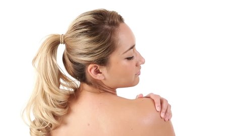 Young Hispanic woman rubbing lotion on her shoulder and back.
