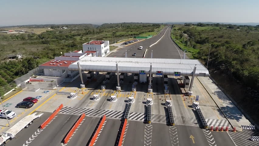 Aerial Shot of a a truck and some cars crossing aTollbooth in the highway in the middle of the countryside in Mexico