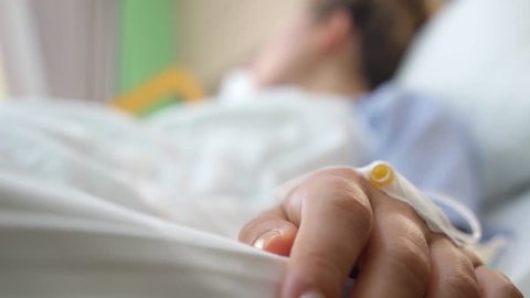 Patient Hand In Hospital Bed Having Drop Bottle Close Up