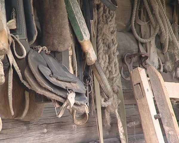 Old wooden house in the village made of logs and variety of ancient tools and utensils hanging on the wall. 