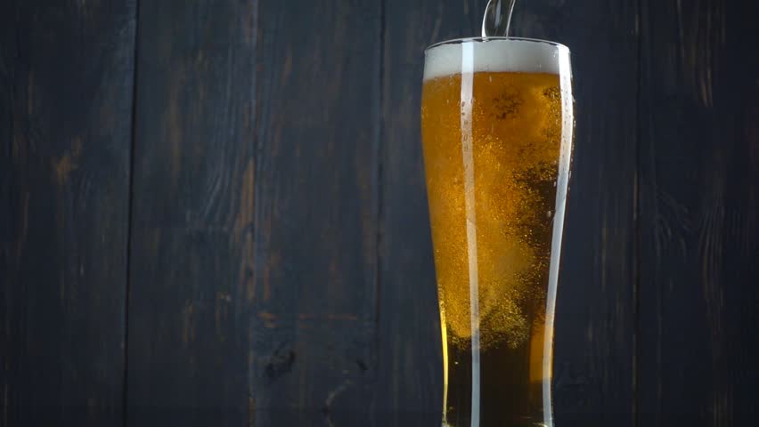 Pouring beer into glass over dark wooden background. Slow motion | Shutterstock HD Video #14622703