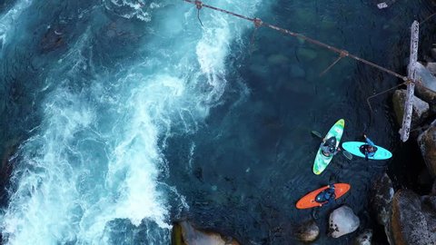 Aerial shot above a group of kayakers preparing to paddle down rapids in water of deep blue river in summer in Patagonia Chile - 2K HD