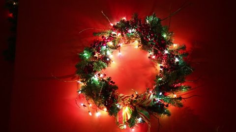 Christmas wreath with illumination on red wall in room
