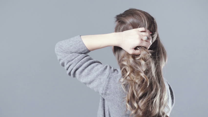 Young beautiful brunette woman posing in studio. Fashion portrait of a beautiful woman. Cheerful woman with long brown hair isolated on grey background.