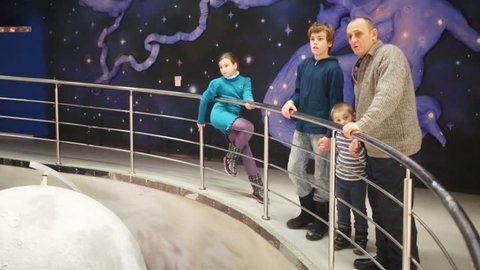 Grandfather and three children look at model of planets in museum