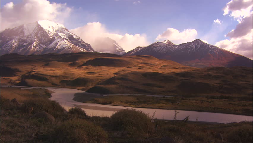 Golden Afternoon Sunlight On Hills With River in Foreground And Cuernos Del