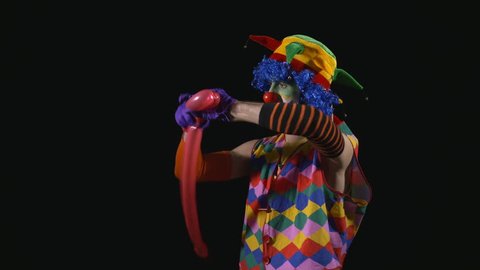 Young funny clown making a dog from a balloon and bursting it with a needle