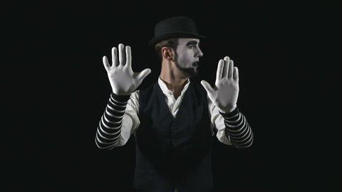 Young funny mime behind an invisible glass box or wall