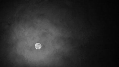 Black and white night time-lapse of the Moon moving behind clouds.
