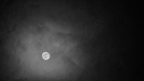 Black and white night time-lapse of the Moon moving behind clouds.