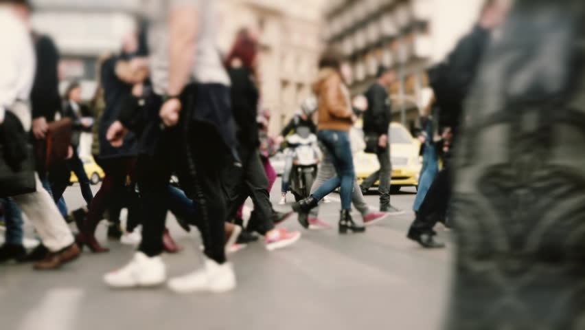 People pedestrians walk/cross big city intersection slow motion 100p.Gimbal stabilized tracking shot of an anonymous crowd mostly of young age getting across a busy city street.No logos/faces visible.