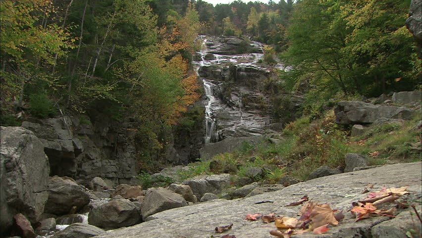 Cascading New England Waterfall With Fall Leaves Blowing In Breeze