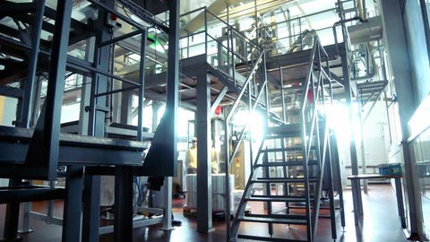 Worker climb metal stairs at modern factory/Interior of milk factory/People work in large shop at dairy factory/Milk processing line/Food processing plant/Industrial workshop at factory/Food industry