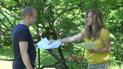 Angry man husband and woman wife disagree with divorce documents in garden yard. Static shot. 4K