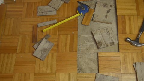 Handyman removing pieces of parquet damaged by moisture or water
