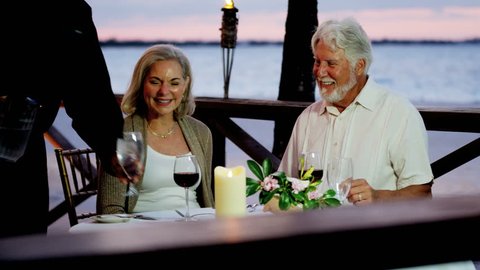Caucasian senior couple enjoying evening beachfront dining