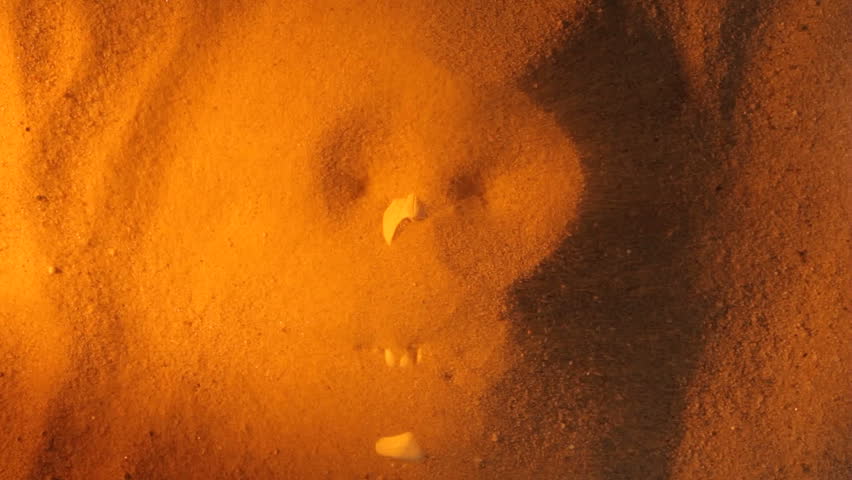 Sand blows away to reveal a human skull