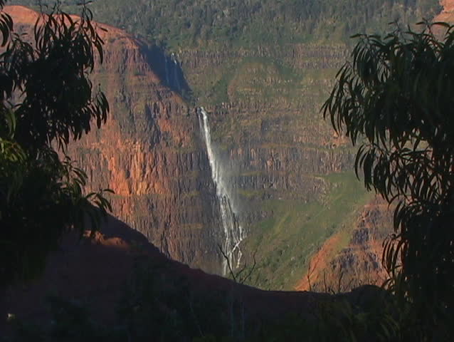 A rocky ledge is a perfect vantage point for viewing a mountain lake and waterfall cascading down a steep incline.