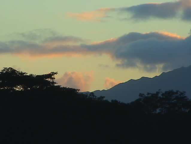 Sky above silhouetted mountains is filled with clouds of many hues.
