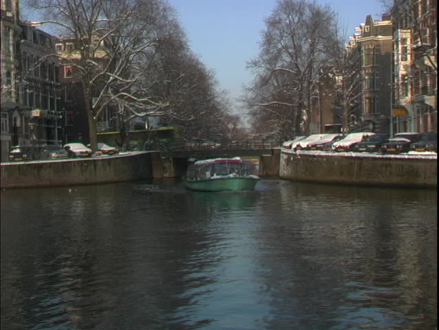 A water taxi travels through a canal in Amsterdam.