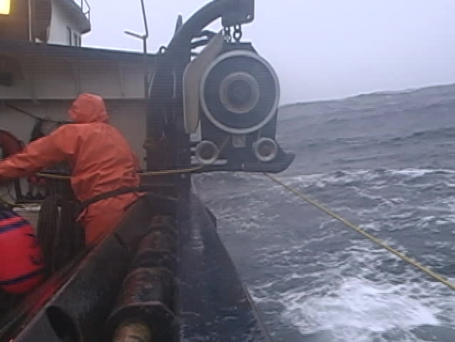 A lobster fishermen throws a rope out and catches a buoy in treacherous conditions while ocean fishing.
