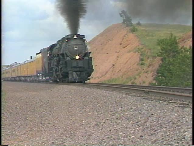 Tracking-out shot of a Union Pacific steam passenger train on a rural track in Colorado.